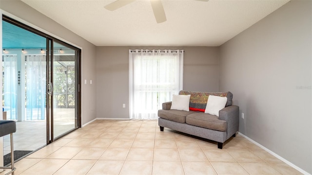 living area featuring baseboards, a ceiling fan, and light tile patterned flooring