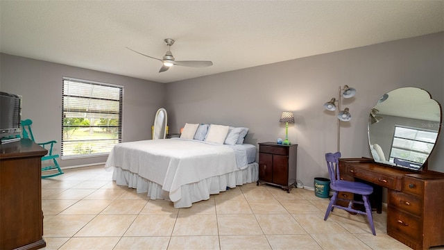 bedroom featuring ceiling fan, baseboards, a textured ceiling, and light tile patterned flooring