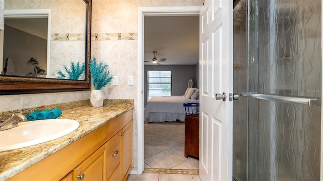 ensuite bathroom with connected bathroom, a ceiling fan, tile walls, vanity, and tile patterned floors