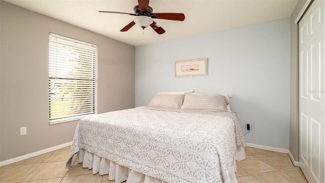 bedroom featuring light tile patterned floors, multiple windows, baseboards, and a closet