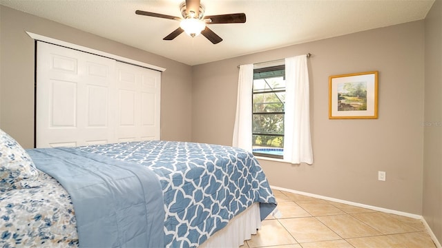 bedroom featuring light tile patterned floors, a closet, a ceiling fan, and baseboards