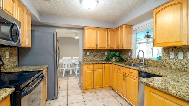 kitchen featuring light tile patterned flooring, light stone countertops, a sink, and stainless steel appliances