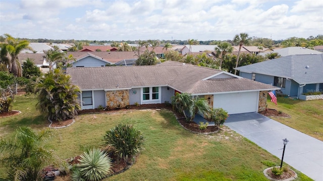 ranch-style home featuring a garage, concrete driveway, a front yard, and a residential view