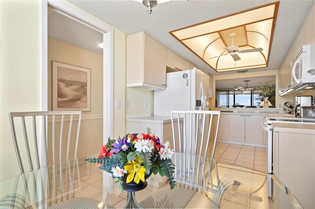 5740 Midnight Pass Rd Unit 402, Sarasota, FL 34242 - kitchen with a textured ceiling, light tile patterned floors, white appliances, white cabinets, and light countertops