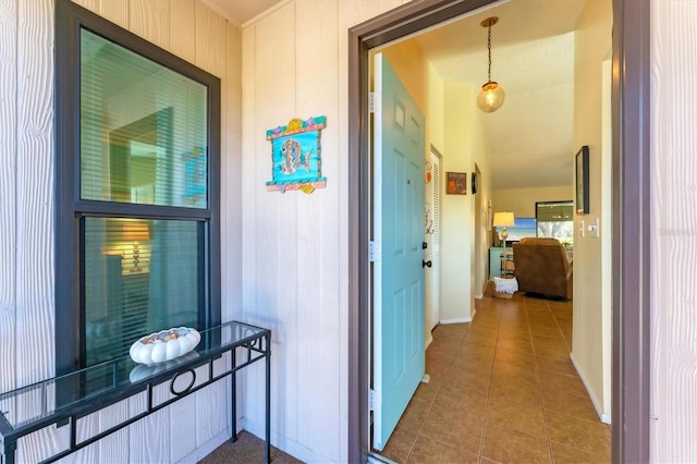 corridor featuring lofted ceiling, baseboards, and tile patterned floors