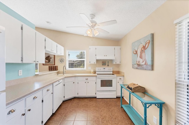 kitchen with white appliances, light tile patterned flooring, a sink, and white cabinets