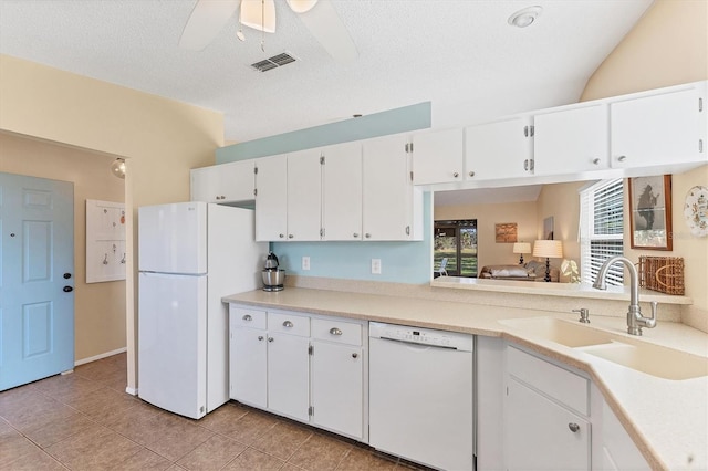 kitchen with light countertops, visible vents, white cabinets, a sink, and white appliances