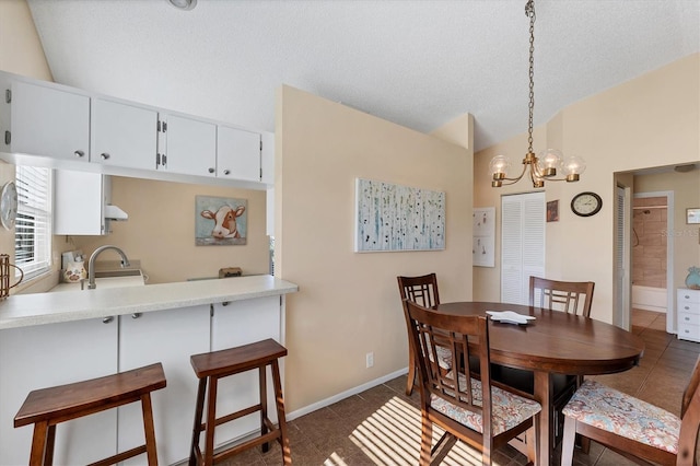 dining area featuring lofted ceiling, dark tile patterned floors, a textured ceiling, and baseboards