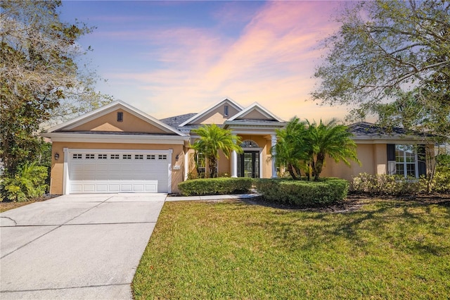 view of front of home with a garage, stucco siding, concrete driveway, and a yard