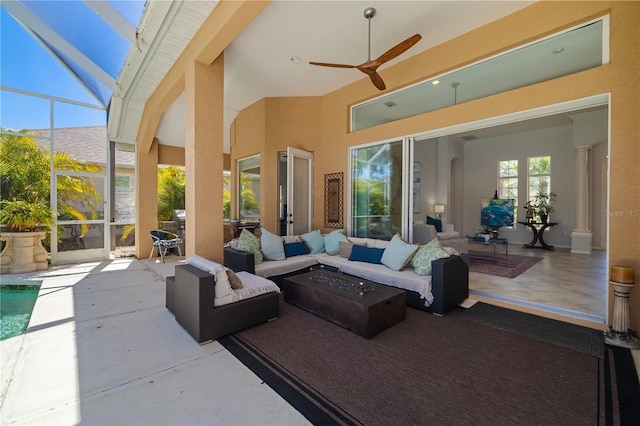 view of patio featuring a lanai, a ceiling fan, and an outdoor living space with a fire pit