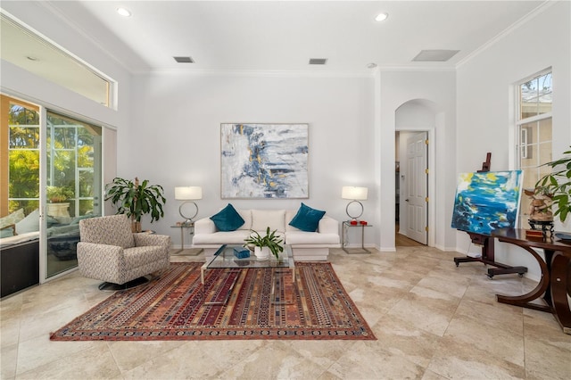 living room featuring a healthy amount of sunlight, baseboards, ornamental molding, and arched walkways