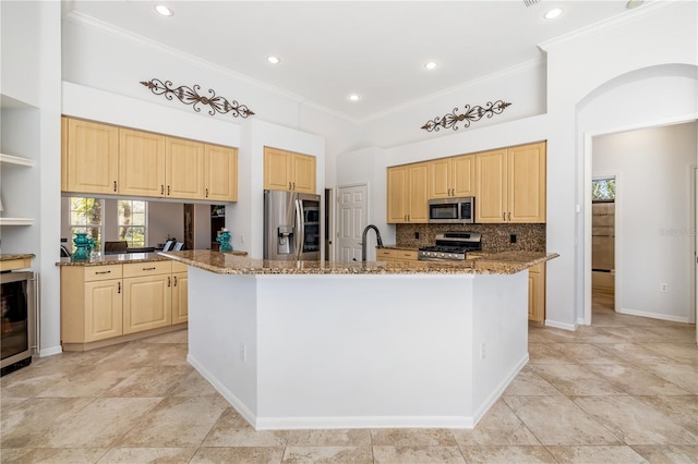 kitchen featuring light brown cabinets, a kitchen island with sink, appliances with stainless steel finishes, and crown molding