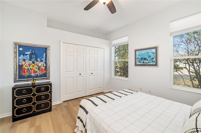 bedroom with light wood-style floors, a closet, ceiling fan, and baseboards