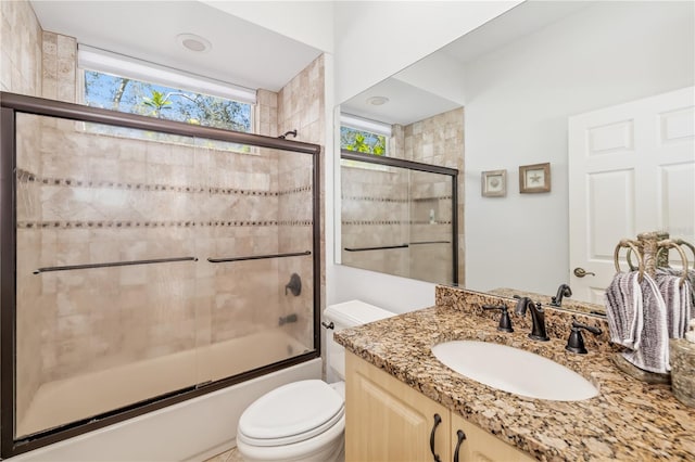 full bathroom featuring toilet, bath / shower combo with glass door, and vanity