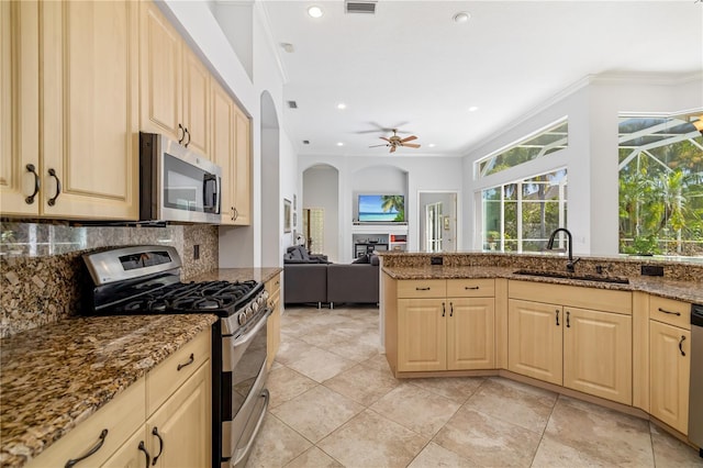 kitchen featuring appliances with stainless steel finishes, ornamental molding, a sink, a fireplace, and backsplash