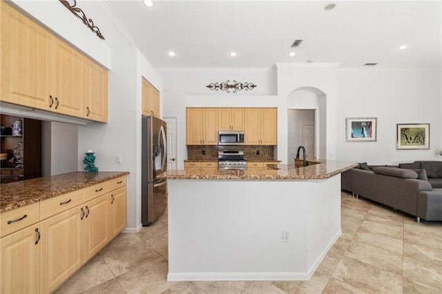 kitchen with stainless steel appliances, tasteful backsplash, visible vents, light brown cabinetry, and dark stone countertops