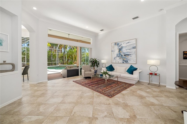 living area with arched walkways, recessed lighting, visible vents, baseboards, and crown molding