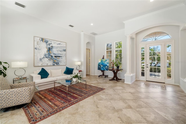 living area with crown molding, baseboards, visible vents, and ornate columns