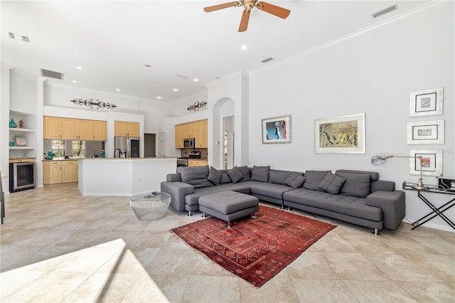 living room with a towering ceiling, visible vents, and ornamental molding