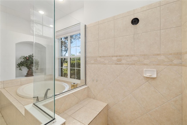 full bathroom with tiled shower and a bath