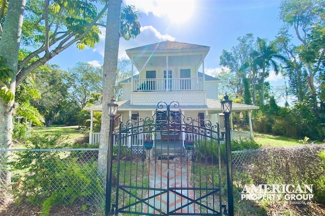 view of front of house featuring a balcony, a fenced front yard, a gate, and a porch