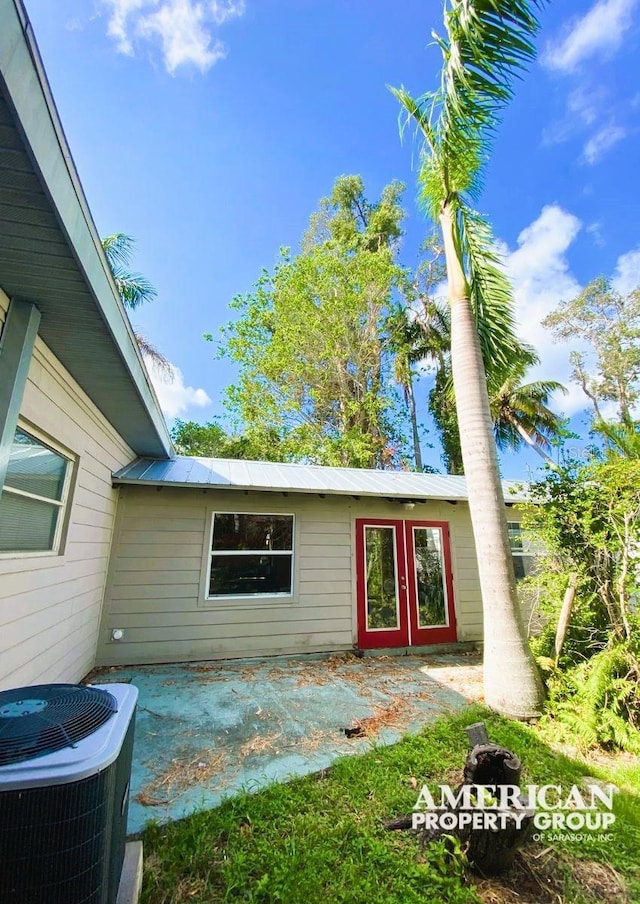 view of exterior entry with metal roof, a patio, and central air condition unit