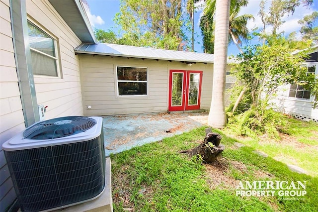 doorway to property with metal roof, central AC unit, and a patio