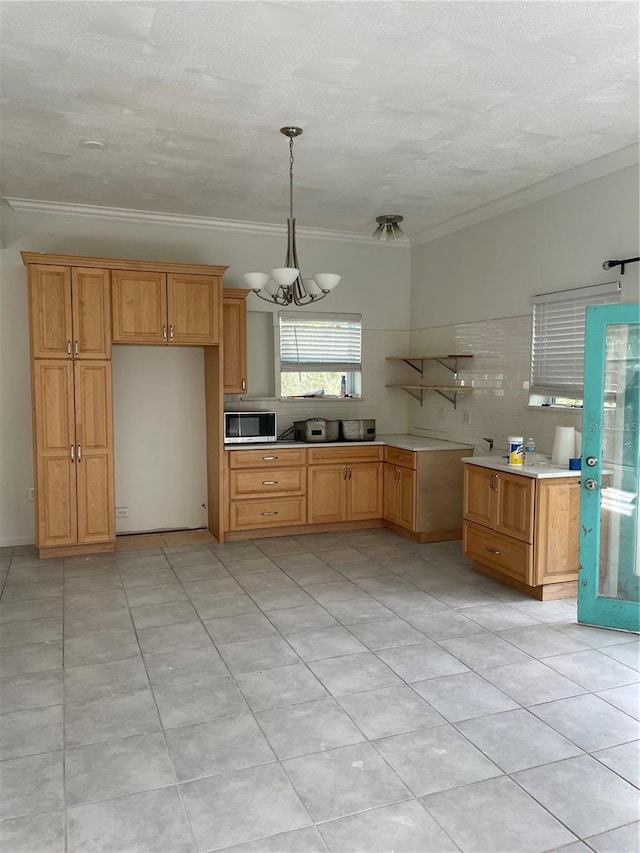 kitchen with open shelves, ornamental molding, stainless steel microwave, and light countertops