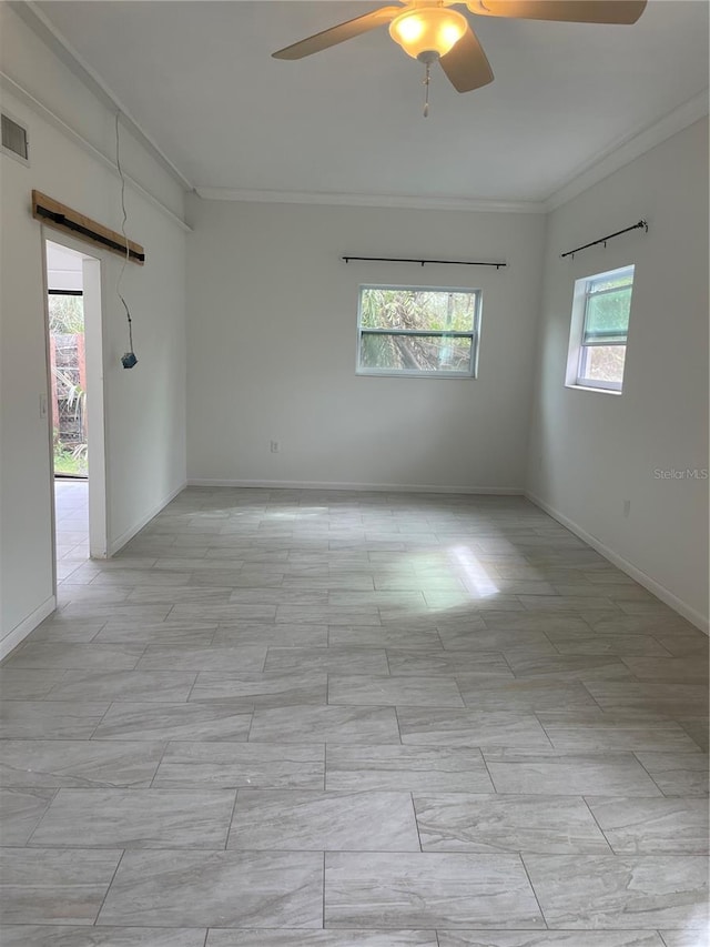 spare room with baseboards, visible vents, ornamental molding, and ceiling fan