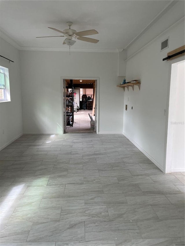 spare room featuring crown molding, visible vents, a barn door, a ceiling fan, and baseboards