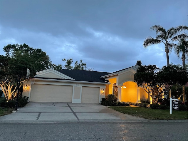 single story home with a garage, driveway, a front yard, and stucco siding