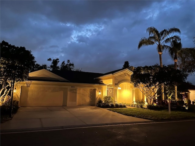 view of front of house with an attached garage, concrete driveway, and stucco siding