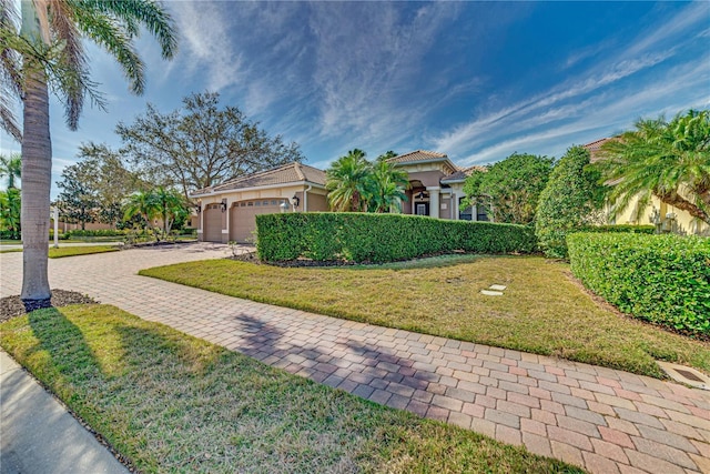 view of front of house featuring decorative driveway, stucco siding, a garage, a tiled roof, and a front lawn