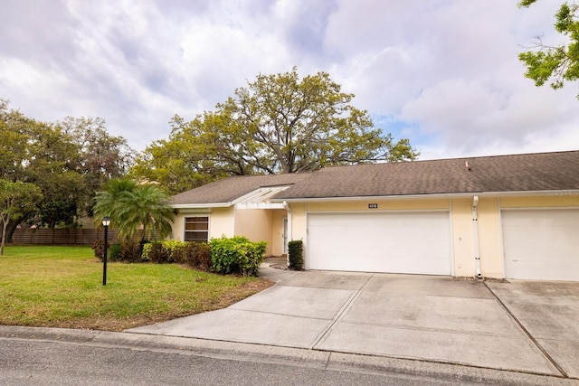 view of front of house with an attached garage, fence, driveway, stucco siding, and a front lawn