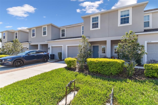 view of property with a garage, concrete driveway, and stucco siding