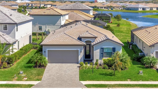 view of front of house featuring a residential view, a tiled roof, an attached garage, a water view, and decorative driveway