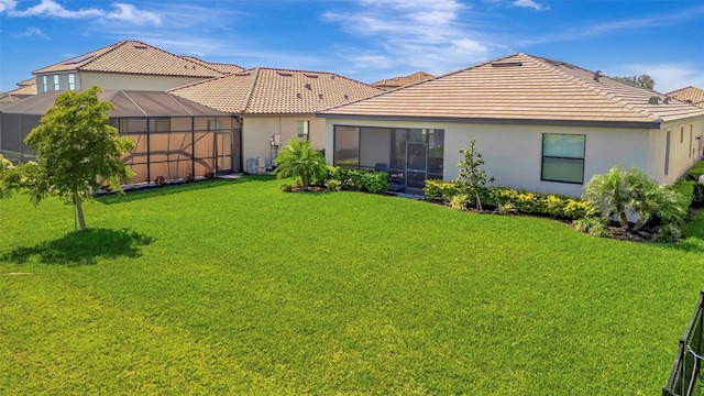 rear view of property with stucco siding, a tiled roof, and a yard