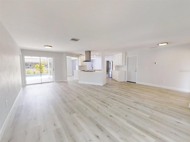 unfurnished living room featuring light wood-type flooring, baseboards, and visible vents