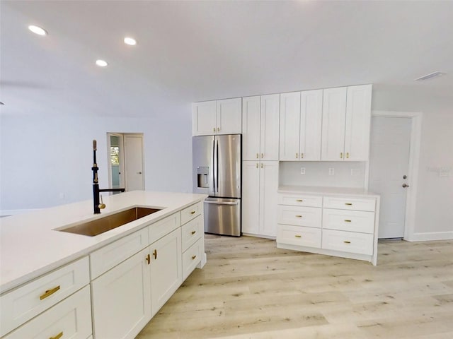 kitchen with stainless steel fridge, light countertops, and a sink