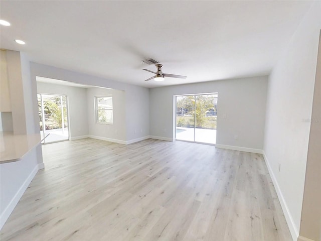 spare room featuring baseboards, light wood-style floors, visible vents, and a healthy amount of sunlight