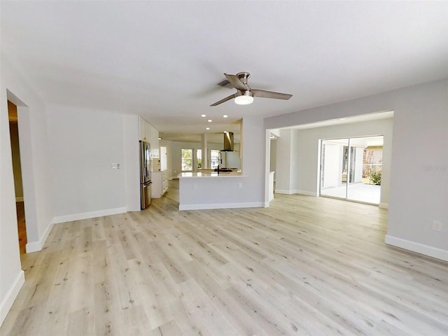 unfurnished living room featuring light wood-style floors, plenty of natural light, baseboards, and ceiling fan