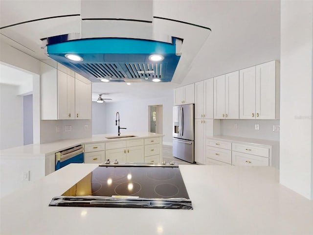 kitchen with white cabinets, a sink, stainless steel fridge, dishwasher, and a peninsula