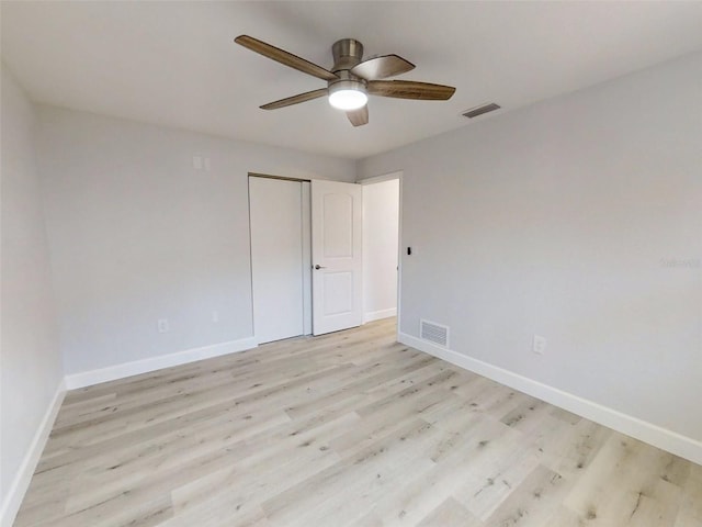 empty room featuring light wood-type flooring, visible vents, and baseboards