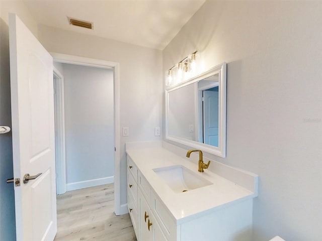 bathroom with wood finished floors, vanity, visible vents, and baseboards