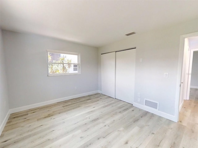 unfurnished bedroom with baseboards, a closet, visible vents, and light wood-style floors