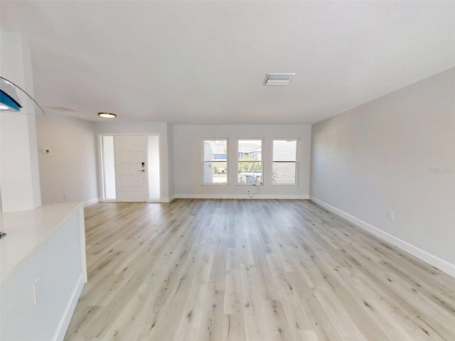 unfurnished living room with light wood finished floors, visible vents, and baseboards