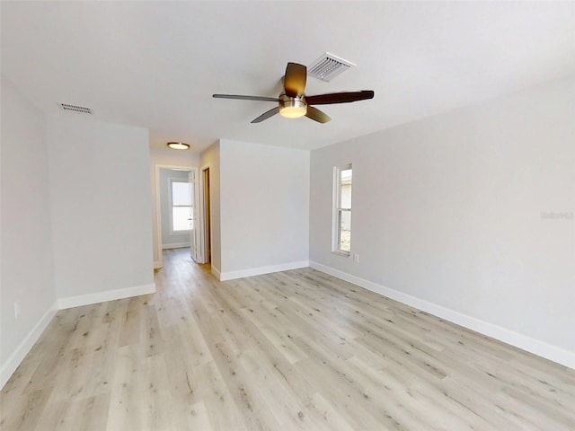 empty room featuring light wood finished floors, baseboards, visible vents, and a ceiling fan