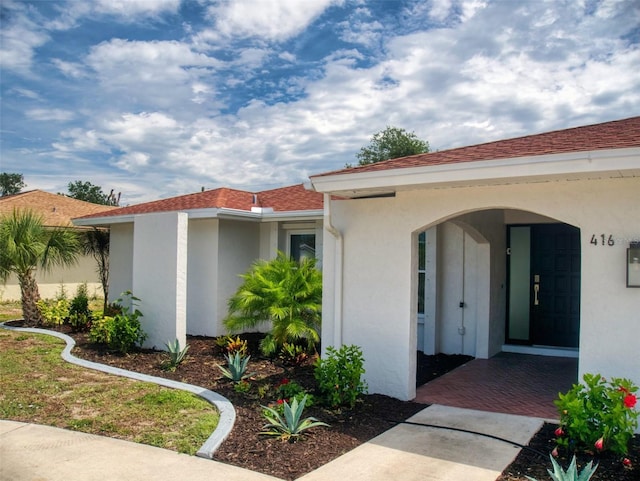 property entrance featuring roof with shingles and stucco siding