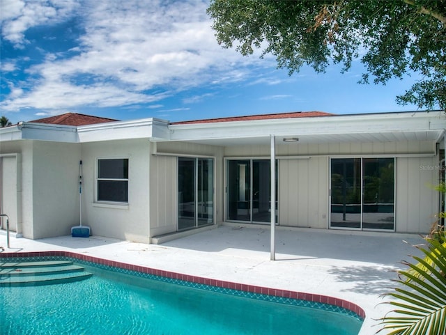 back of property featuring board and batten siding, an outdoor pool, and a patio