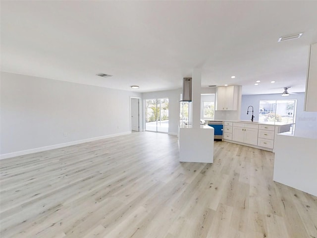 unfurnished living room with light wood-style flooring, recessed lighting, a sink, visible vents, and baseboards